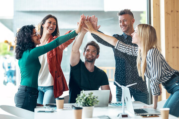 Group of successful smart business team celebrating good job while holding up their right hands on...