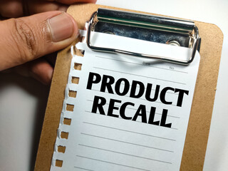 Business concept.Text PRODUCT RECALL on clip board with hand on a white background.