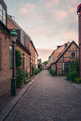 Narrow cobblestoned alley with half-timbered house in old town Lund Sweden during summer sunset