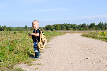 A child with a backpack walks along the road