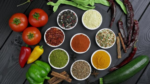 Colorful herbs and spices for cooking. Indian spices. On a black background. Top view