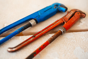 Close-up of adjustable gas wrenches of blue and red colour on wooden table.