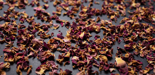 Panoramic photo of dried tea rose leaves, on the black table. Pattern idea.