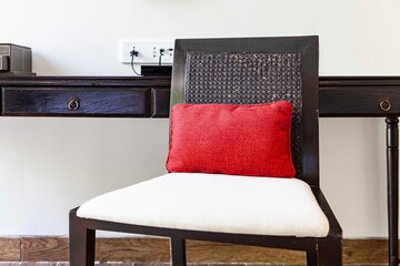 Brown wooden chairs and bright red cushions at the desk in the hotel room