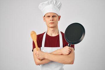 male chef in a white apron Frying pan in hand cooking food