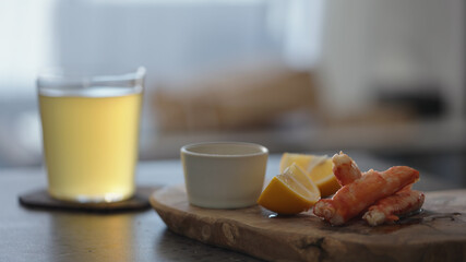 Crab leg meat on a olive board with sweet lemon and dip sauce on concrete countertop