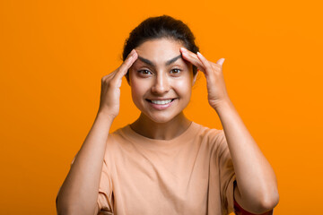 Close up portrait of young indian american woman touching face skin her hands and doing self yoga...