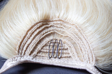 Clip in straight blonde human hair extension close-up. A tress of hair.