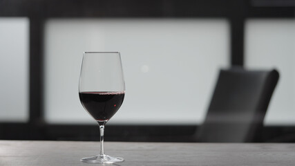 Red wine into wineglass on white oak table with copy space
