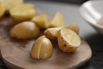 Fototapeta premium Raw washed and chopped baby potatoes ready to cook on olive wood board