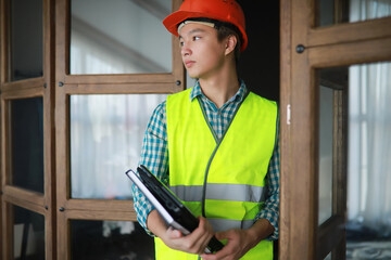 Asian man in protective helmet and construction waistcoat