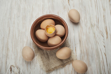 Bowl of raw chicken eggs on the wooden background