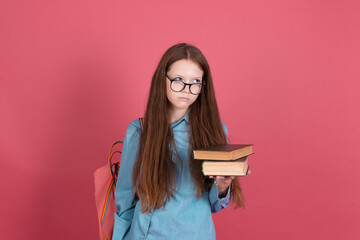 Little kid girl 13 years old isolated on pink background schoolgirl with backpack and books unhappy disappointed hate studying