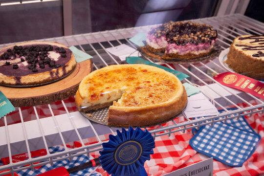 A close up view through the glass of a cold case displaying baked goods with winning entries at the county fair
