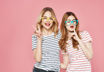 two women stand side by side hug friendship summer fashion pink background