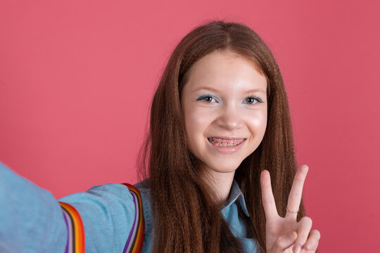 Little kid girl 13 years old in blue denim jacket isolated on red background schoolgirl with backpack take photo selfie