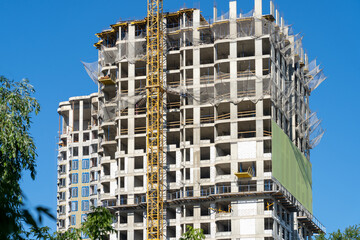 View of frame part of metallic crane machinery attachment at windows of new residential building construction site. Housing construction, apartment block with scaffolding