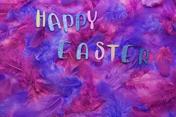 The letters of Happy Easter on colorful feathers with copy space to add text.
