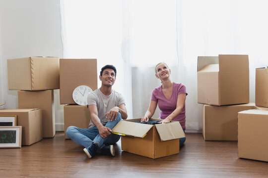Caucasian couple sit on with stuff in boxes moving to new home