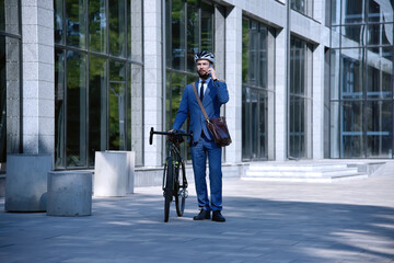 Fototapeta premium Businessman talking on mobile phone with bike.