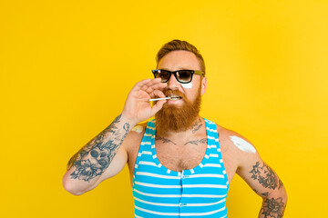 man with beard,tattoo and swimsuit smokes a cigarette