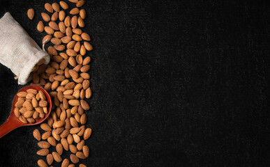 top view of almonds on dark table with wooden spoon or scoop almonds in a wooden bowl beans freely placed on the blackboard