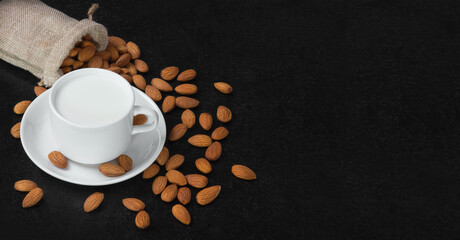 Obraz na płótnie Canvas Almond milk and almonds in wooden cup on dark wooden table Healthy breakfast with copy space