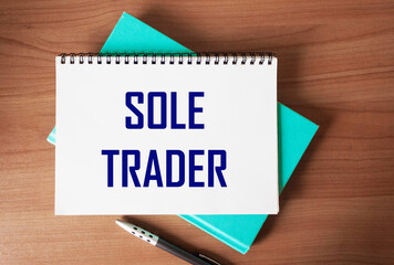 Top view of the written phrase SOLE TRADER, on a wooden background. Business concept.