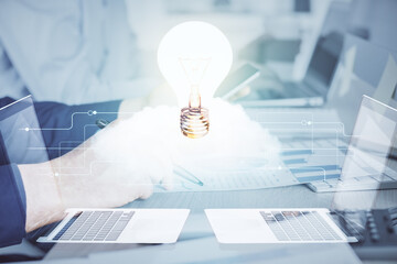 Double exposure of man's hands holding and using a digital device and bulb hologram drawing. Idea concept.