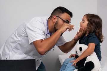 Pediatric doctor examining the throat of his little patient