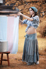 Pregnant woman hanging sheets on the rope for drying