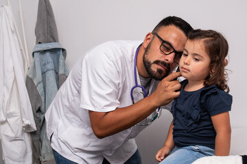 Pediatrician examining the ears of her little patient