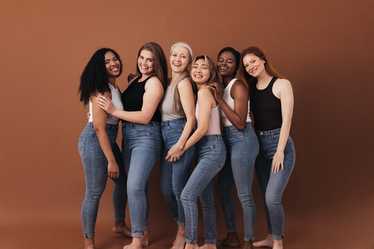 Six women of different ages and body types smiling and laughing over brown background