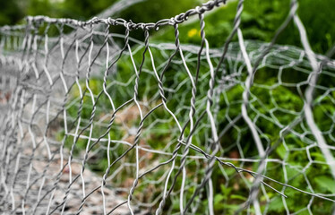 Empty mesh gabion and green grass