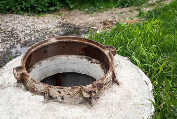 Open manhole without cover danger and green grass