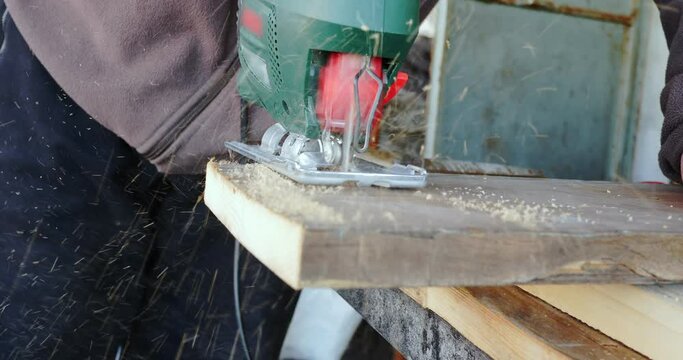 Closeup of a man sawing wood with jigsaw