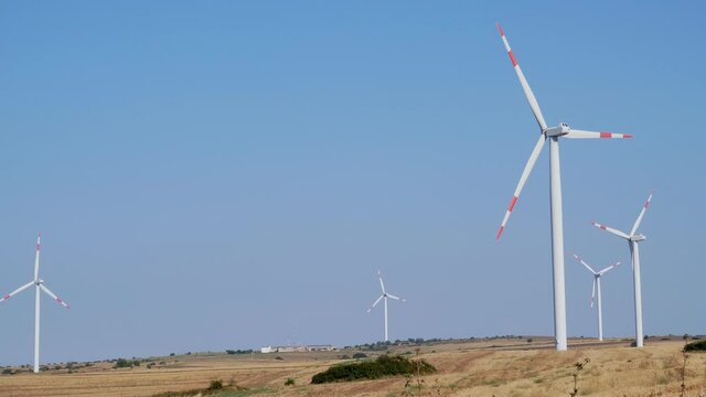 Wind turbines on beautiful sunny summer autumn of the hills of Apuliia (murgia). Curvy road through Eolic park. Green ecological power energy generation. Wind farm eco field
