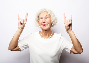 idea, attention and people concept - portrait of smiling senior woman pointing finger up over white background