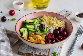 Healthy Salad Bowl with Bulgur, Cherry, Cheese, Cucumber and Walnuts on a light concrete background. Healthy food.