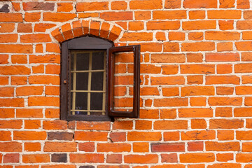 A small window in a gothic church among red bricks.