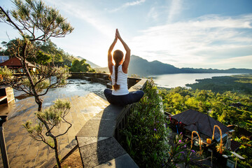 Woman doing yoga at dawn near a volcano on the island of Bali - 445856329