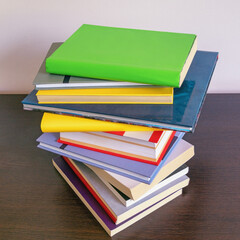 Stack of colorful  books on dark table. Free space for text
