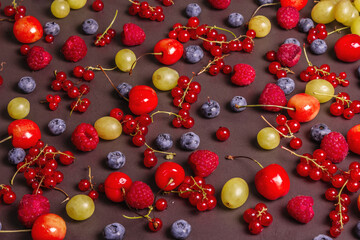 Assorted ripe berries, scattered on a black stone background