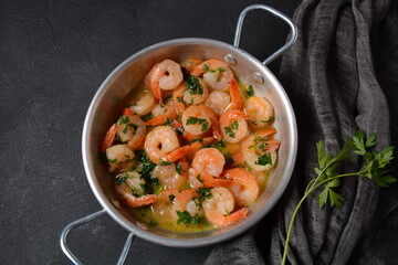 Shrimp scampi with garlic and butter sauce sprinkled with parsley, on a skillet. Keto diet dish