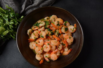 Shrimp scampi with garlic and butter sauce sprinkled with parsley, on a skillet. Keto diet dish