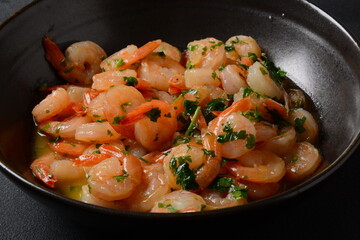 Shrimp scampi with garlic and butter sauce sprinkled with parsley, on a skillet. Keto diet dish