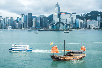 the famous iconic view of Traditional Chinese Sailing boat in the Modern Cityscape, Victoria Harbour, Hong Kong