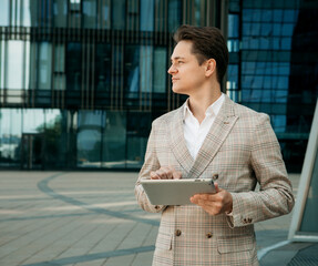 Business, people, tehnology concept: Handsome young businessman with digital tablet by the office...