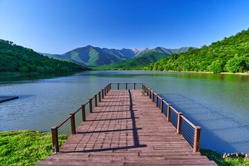 Landscape of wooden pier with beautiful lake and mountains view. Serene quiet peaceful atmosphere in nature