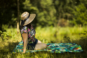 lady in straw hat sitting on a picnic blanket